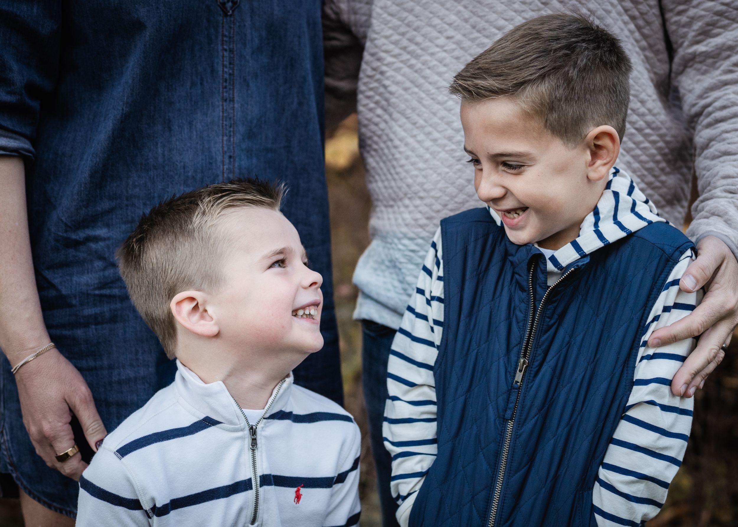 Two young boys in striped shirts share a joyful laugh together while wearing casual clothing.