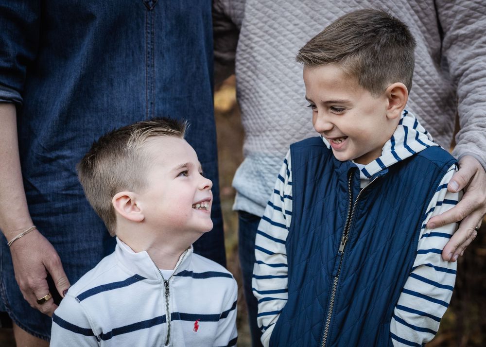 Two young boys in striped shirts share a joyful laugh together while wearing casual clothing.