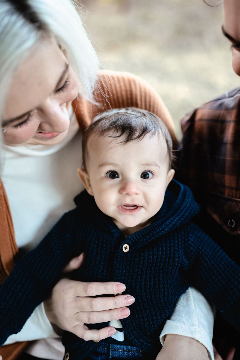 A series of photos showing a baby in a navy sweater being playfully kissed and nuzzled by someone with light hair.
