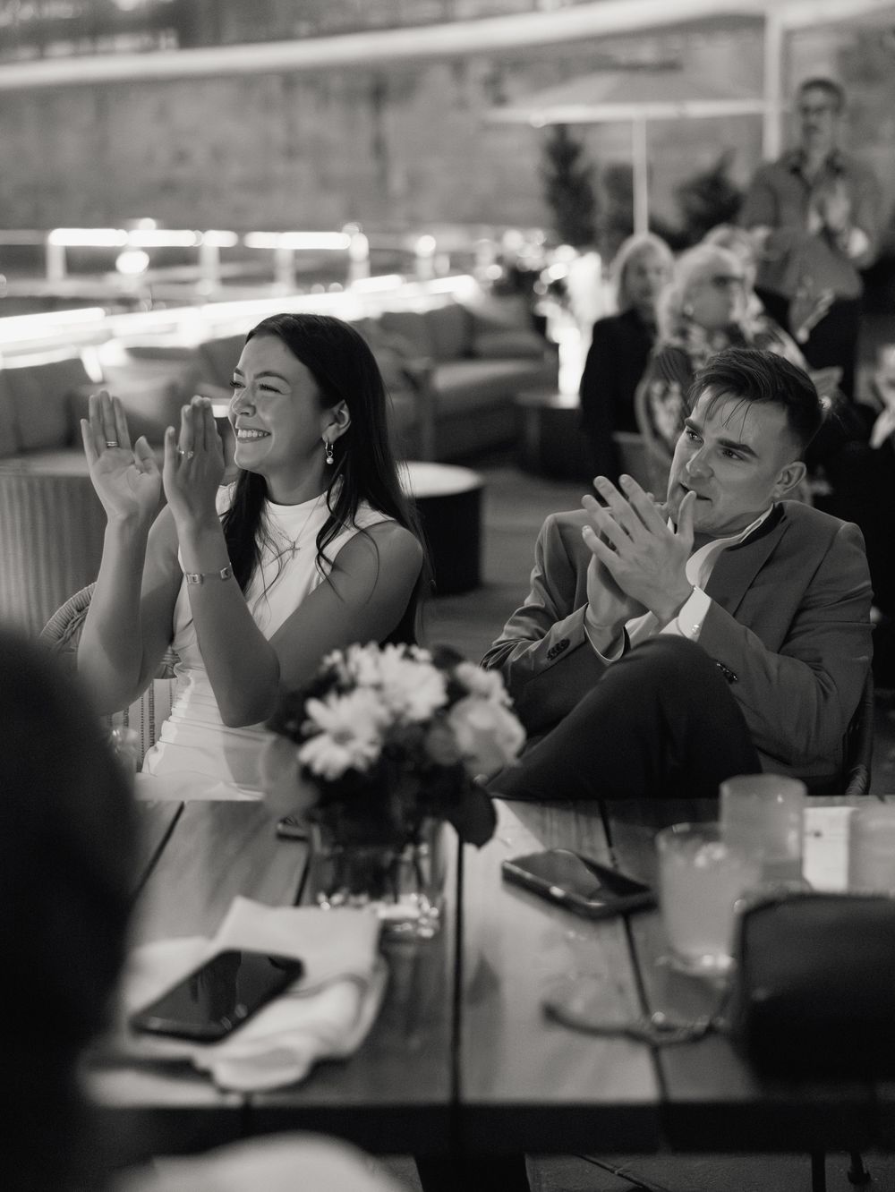 Wedding guests drinking champagne during reception toasts in black and white photography.