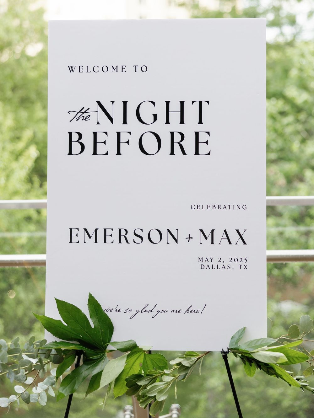 Wedding welcome signage with greenery decorations displaying event details for a Dallas celebration.