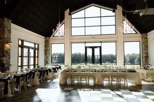 Elegant reception hall with floor-to-ceiling windows and white table settings for a wedding celebration.