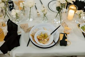 An elegant wedding reception place setting with white linens, candles, and floral arrangements.