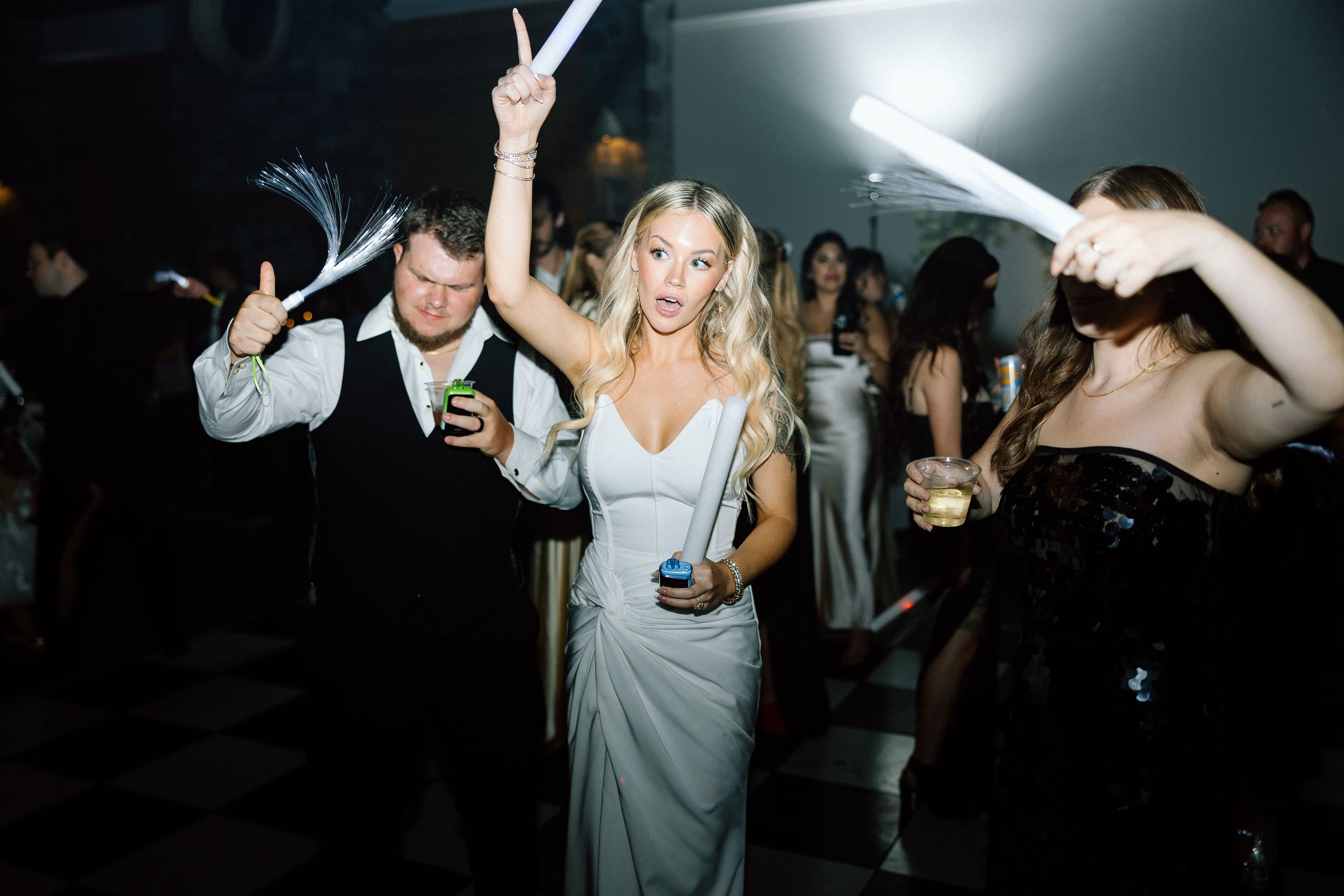 Wedding reception dance party with guests celebrating on a dark dance floor.