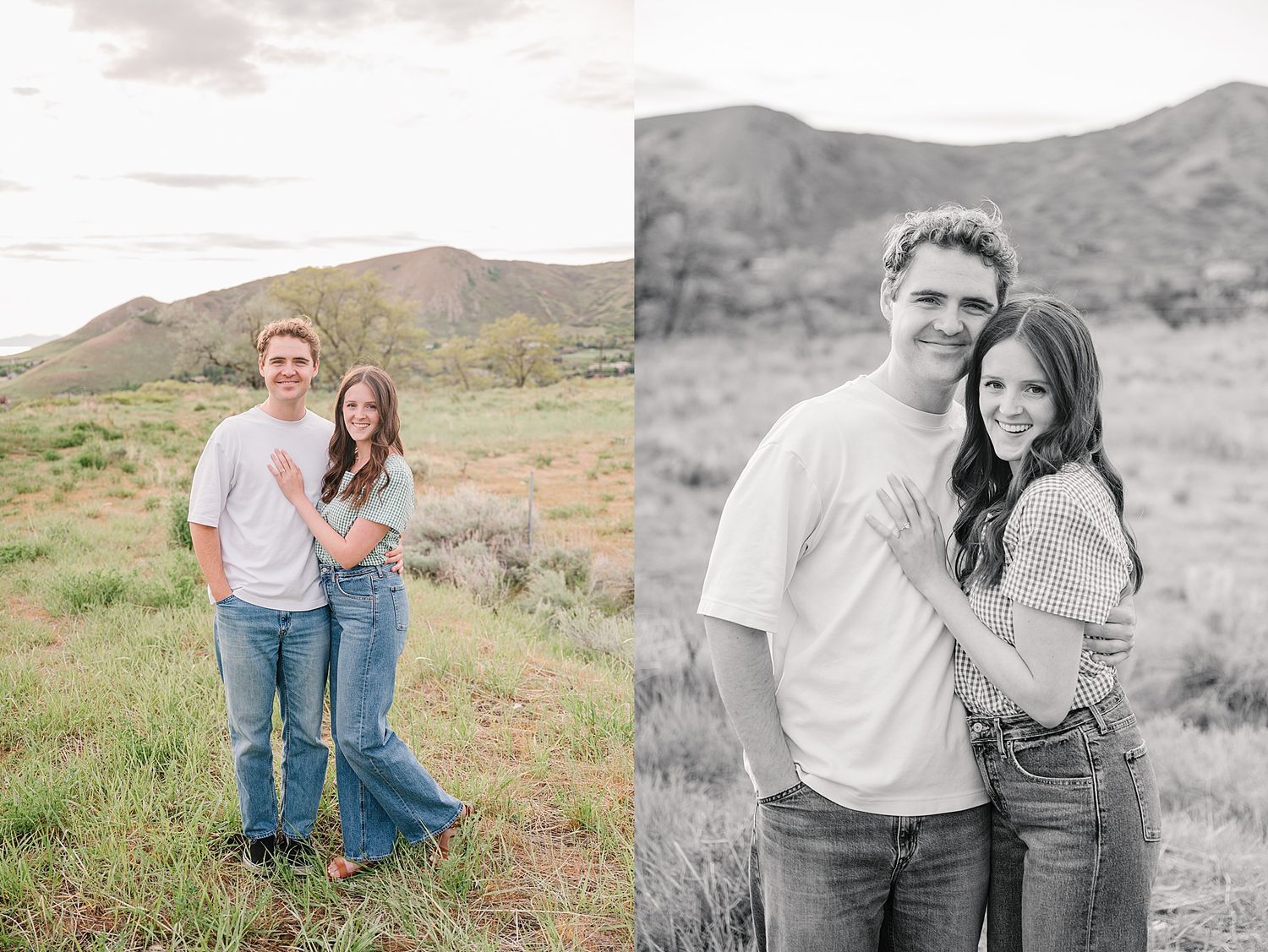 A joyful couple stands together in casual attire against a scenic mountain backdrop on grassy terrain.