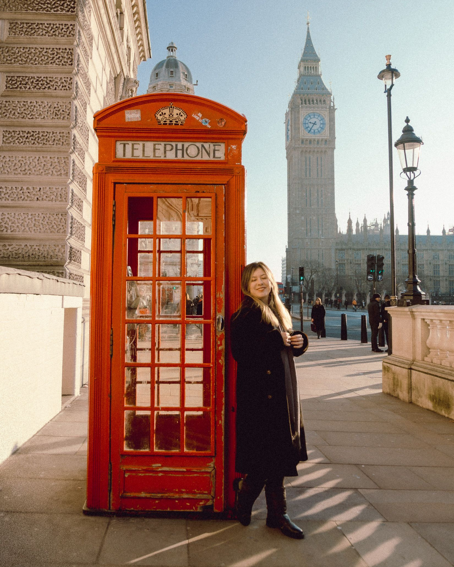 Classic red London phone booth with Big Ben visible in the distance.