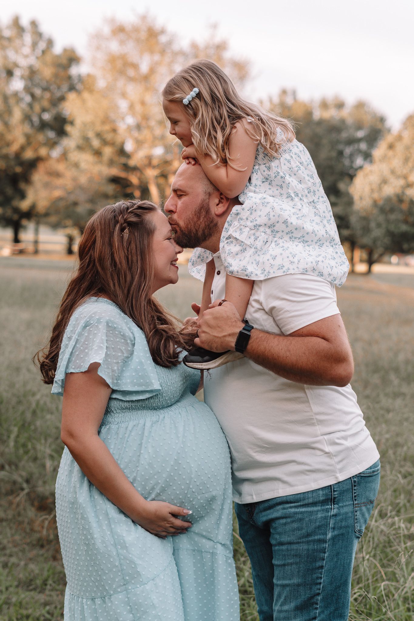 Sweet candid moments captured between two people in a grassy field at sunset.