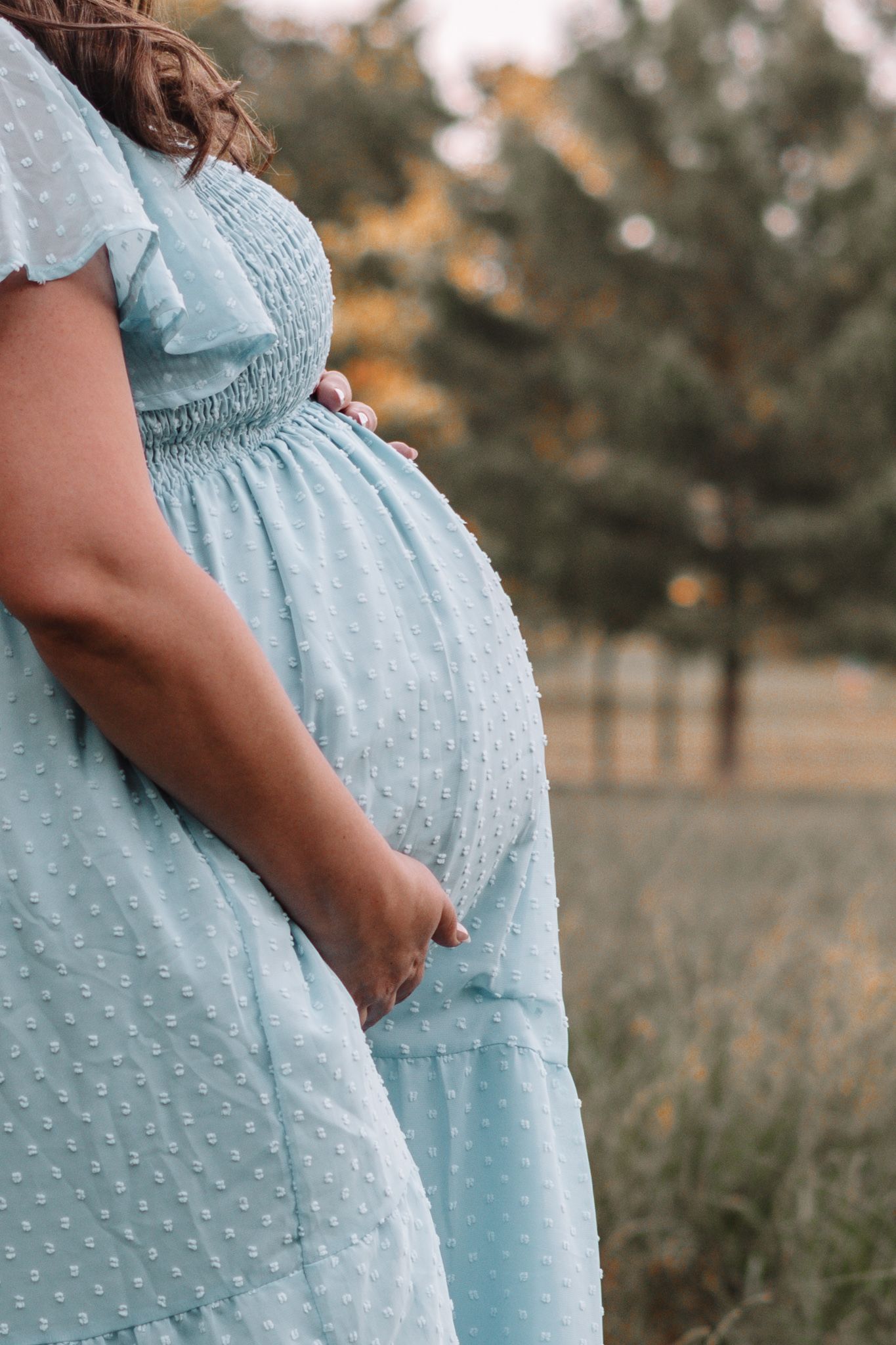 Close-up shots of a light blue polka dot maternity dress in natural outdoor lighting.