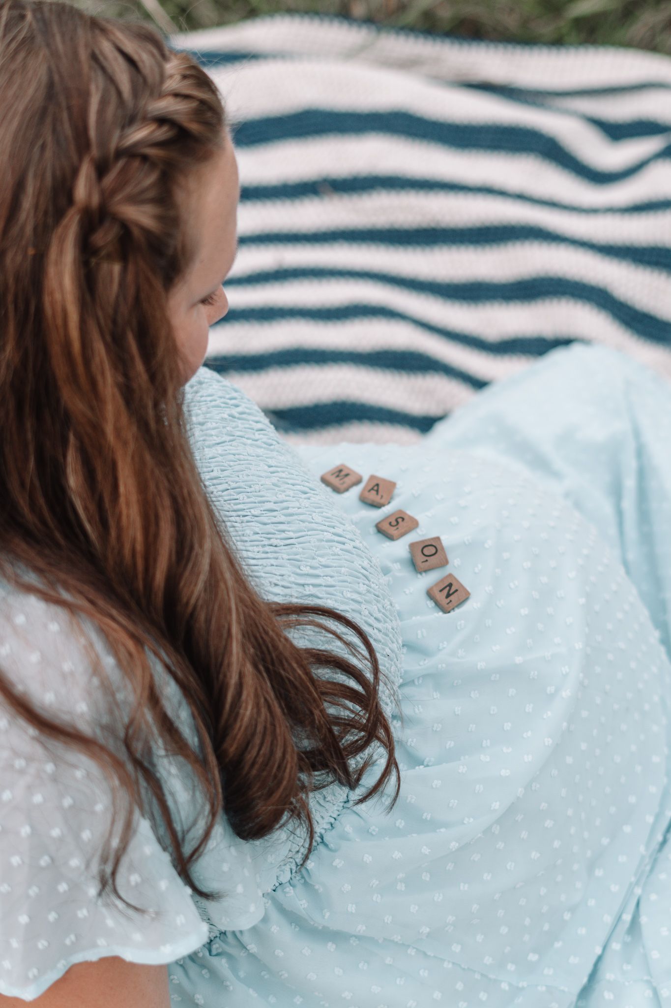 Detail shot of a light blue dotted dress against a striped blanket outdoors.
