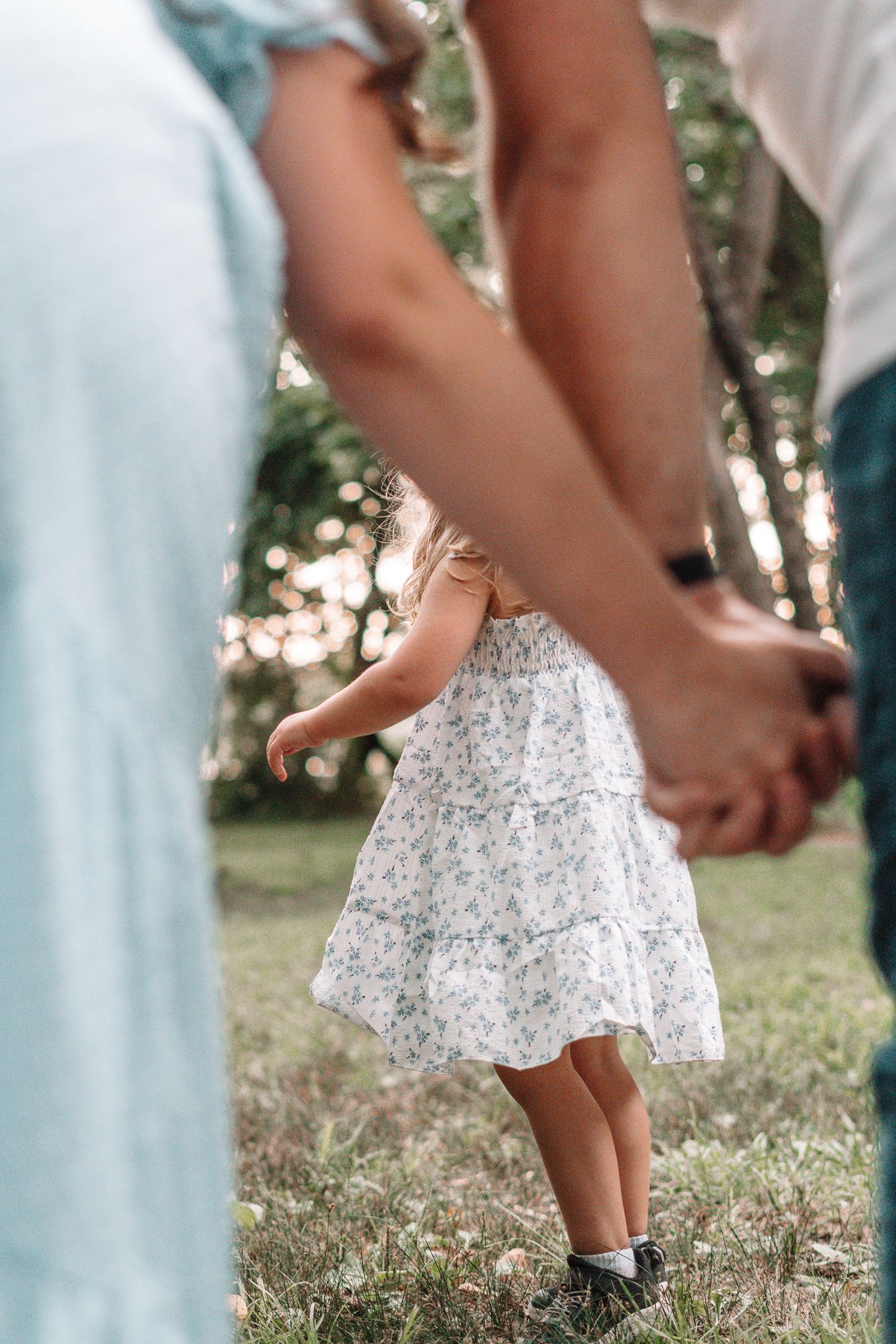 Close-up view of feet and flowy white dress details in a garden setting.