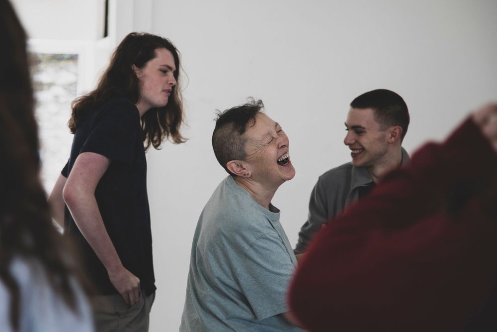 A group of people share a candid laughing moment together during a casual indoor gathering.