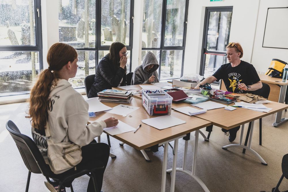 Students working together in a modern classroom with large windows and natural lighting.