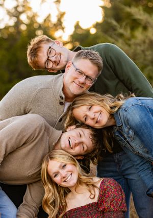 A happy group poses together outdoors at sunset with warm lighting and natural smiles.