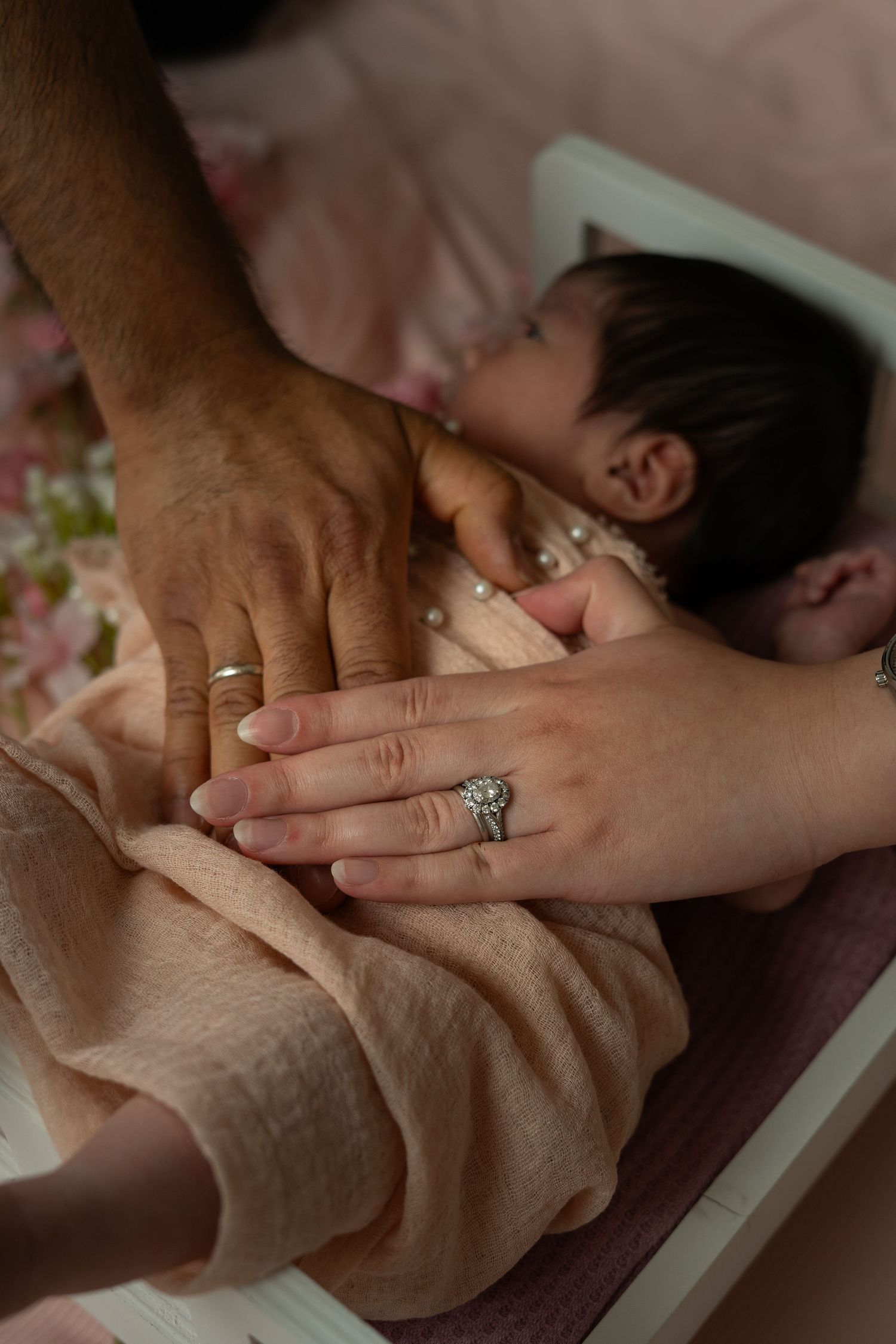 Close up of hands with engagement ring being held together in tender moment.