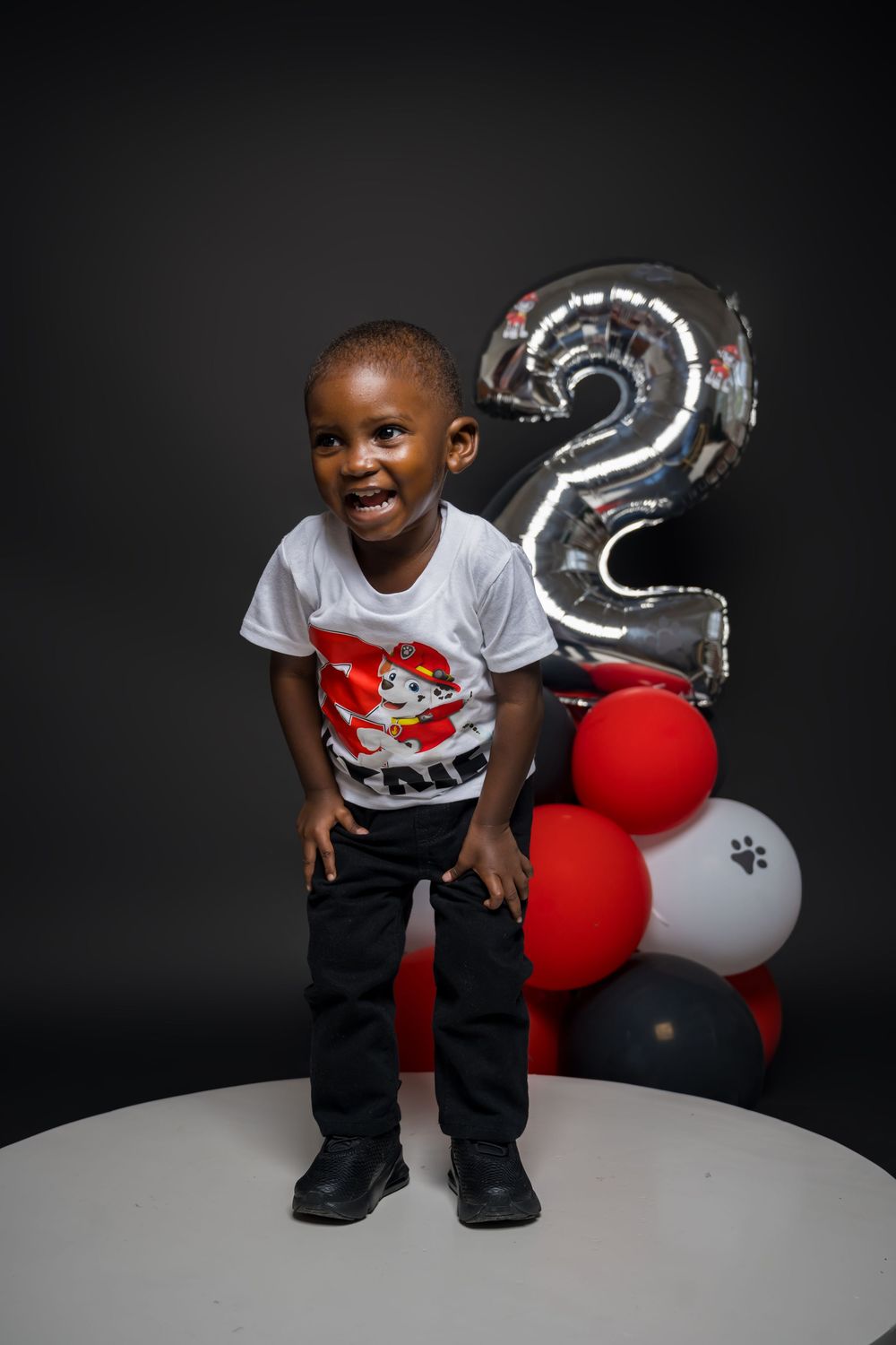 A birthday celebration setup with silver number 2 balloon and red and white decorations.