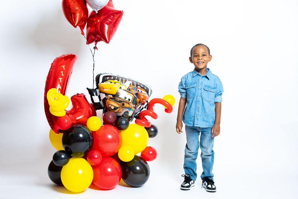 Festive setup with red, yellow and black balloon arrangement and toys.