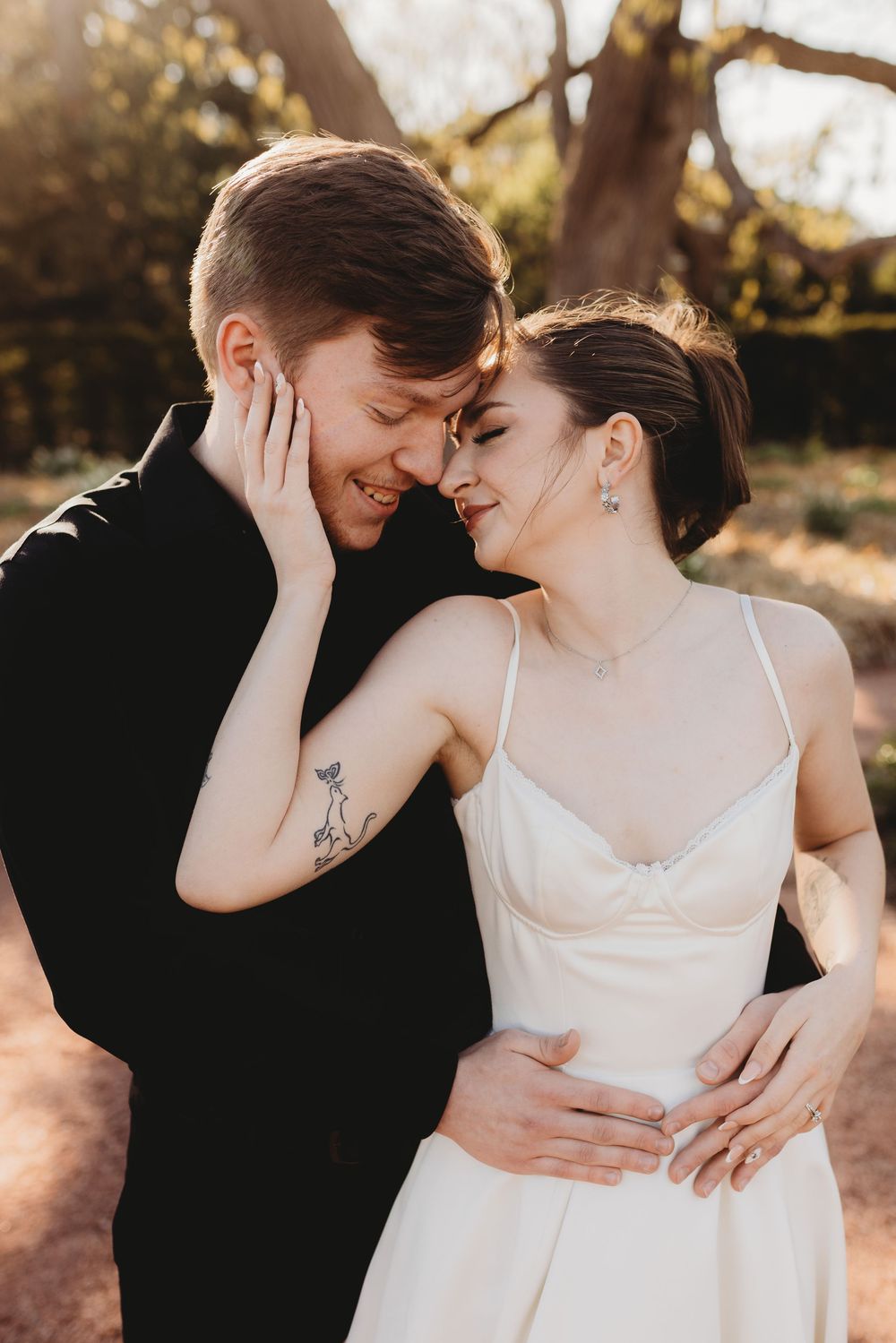Intimate wedding portrait showing tender embrace against natural outdoor backdrop.