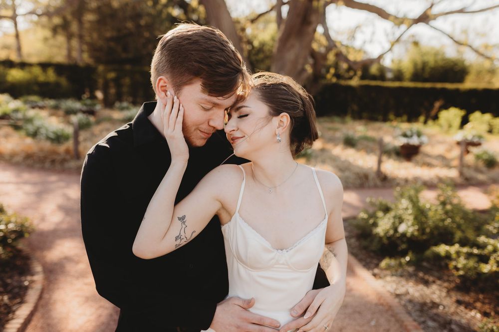 Wedding couple shares tender moments in a sunlit garden setting.