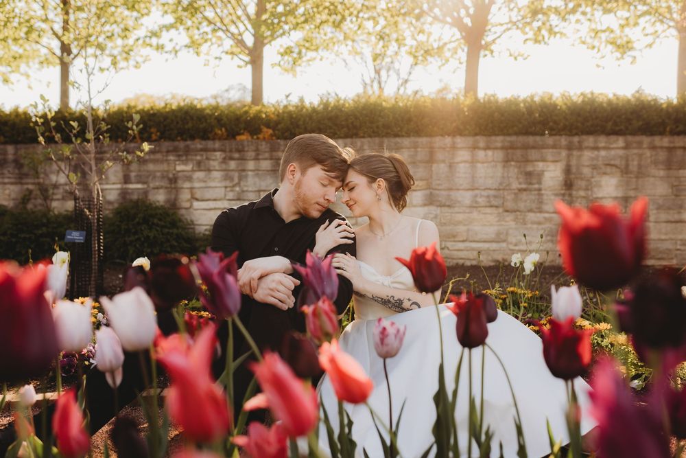 Romantic wedding portrait among blooming tulips at golden hour.