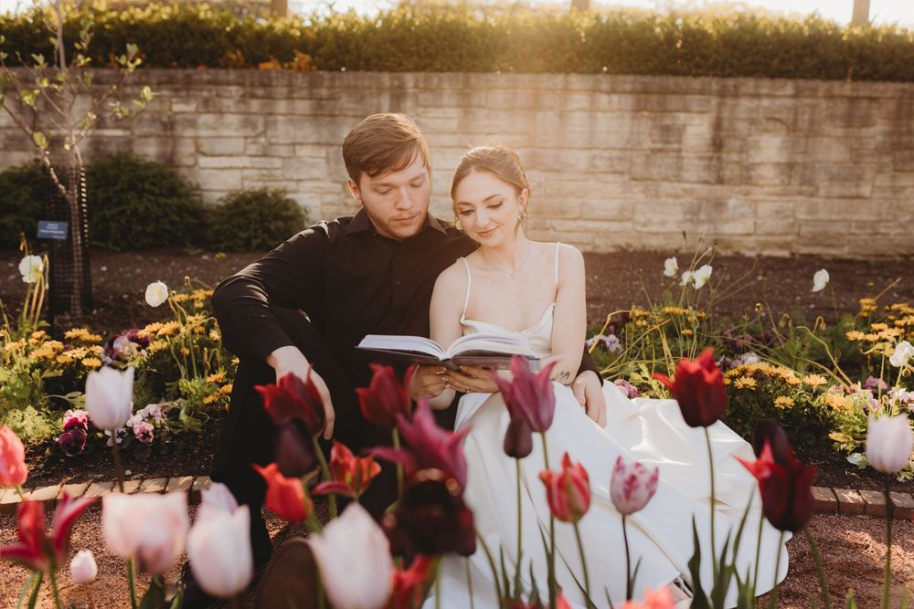 Newlyweds share an intimate moment in a garden with pink and white tulips blooming.