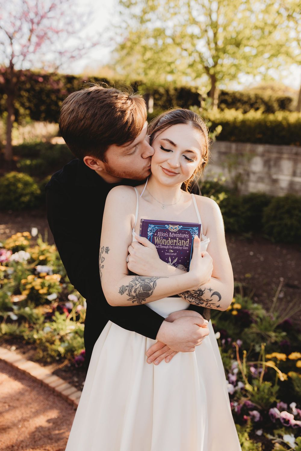 Couple sharing intimate moment while holding book in blooming garden.
