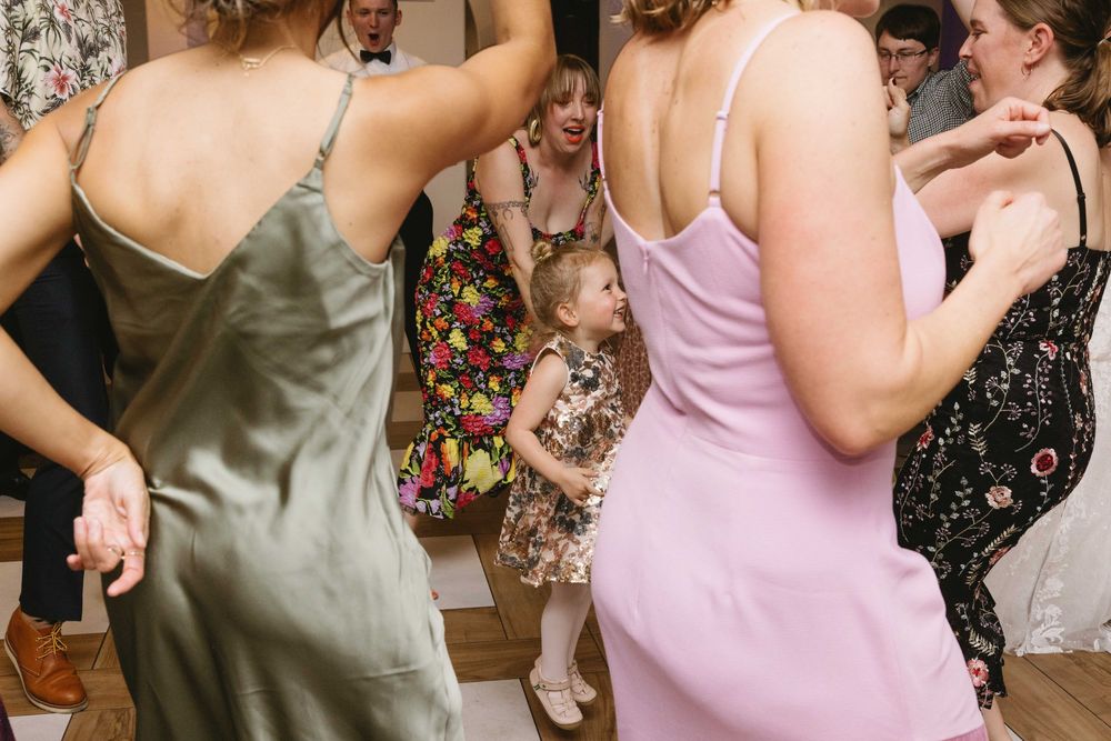 Energetic partygoers in sleek satin dresses dance together at a celebratory gathering.