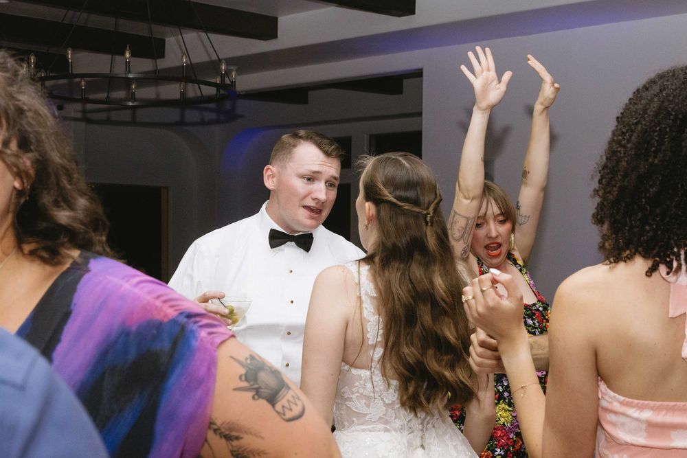 Wedding reception guests dancing energetically together on the dance floor.