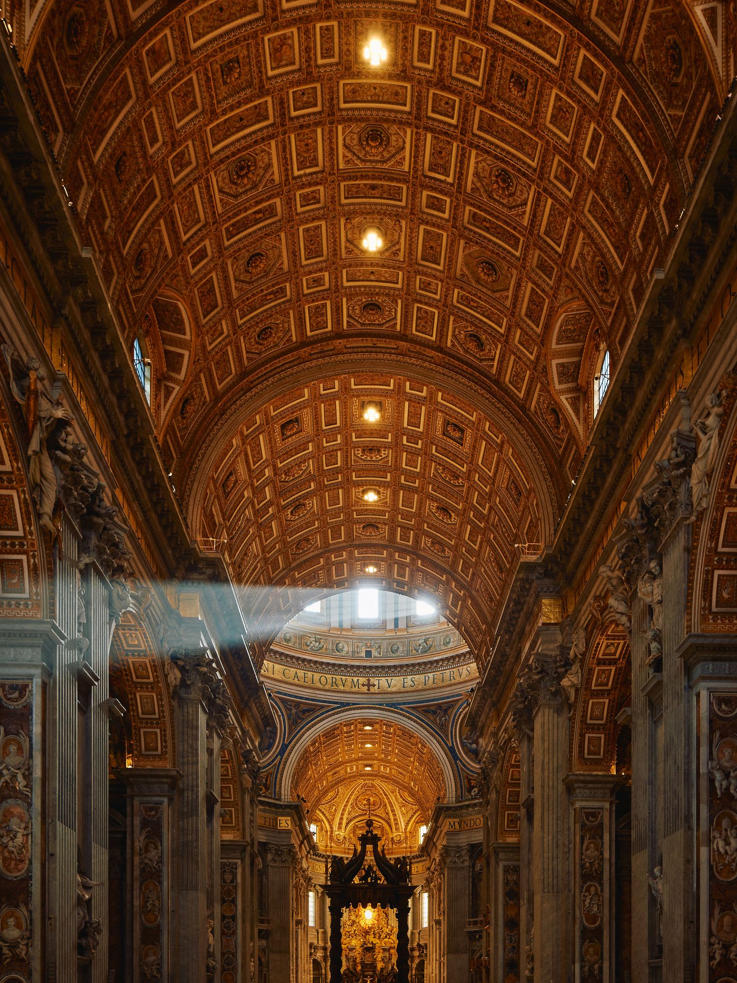 Interior view of St. Peter's Basilica in Vatican City showing ornate coffered ceiling and sunbeams streaming through dome.
