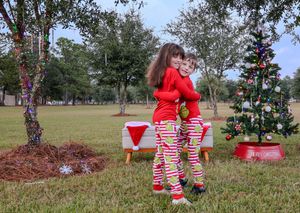 Christmas decor in an outdoor yard with a decorated tree, red and white striped pajamas, and festive decorations.