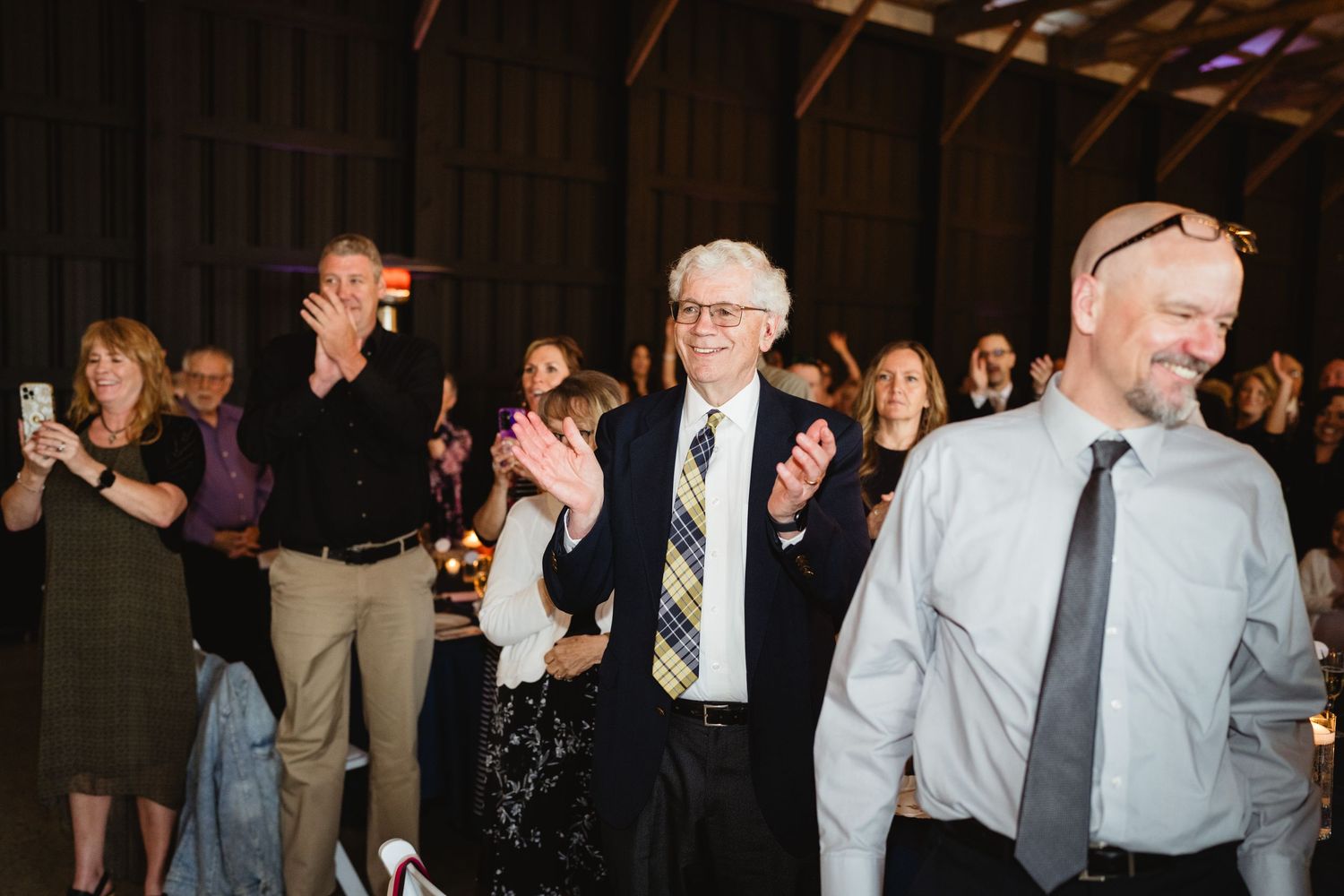 Guests dance and celebrate at an indoor reception party with warm lighting and festive atmosphere.