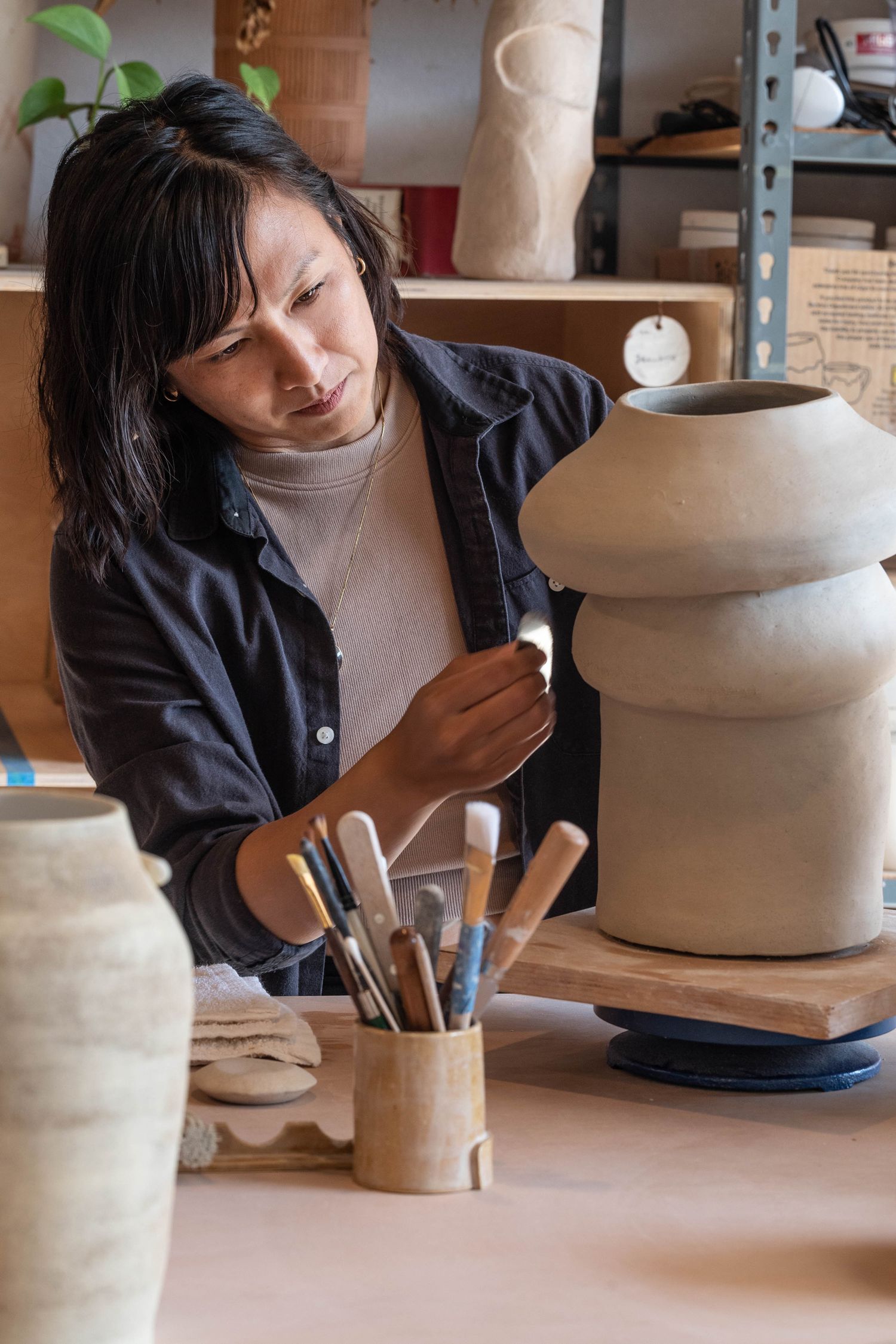 Woman focuses on her clay sculpture in her pottery studio