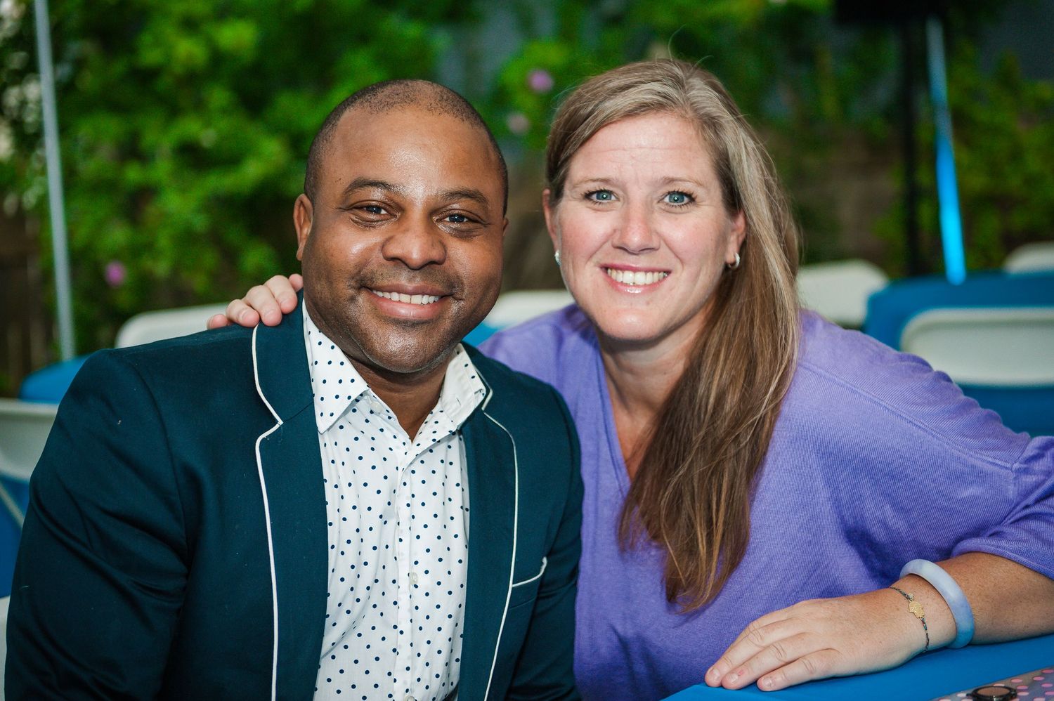 A smiling man and woman pose closely together at an outdoor celebration event.