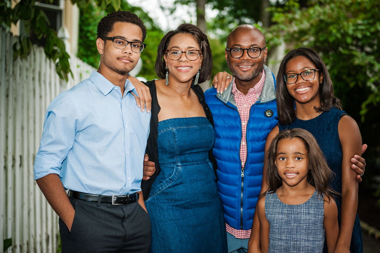 A happy family of five poses together outdoors at a backyard celebration event.