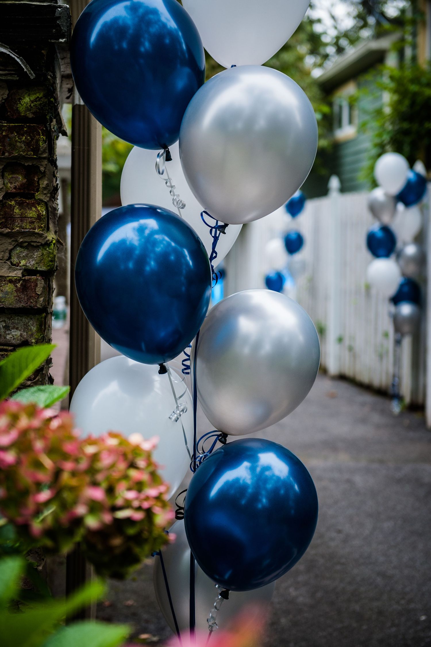 Close-up of shiny navy blue and silver metallic balloons at an outdoor celebration.
