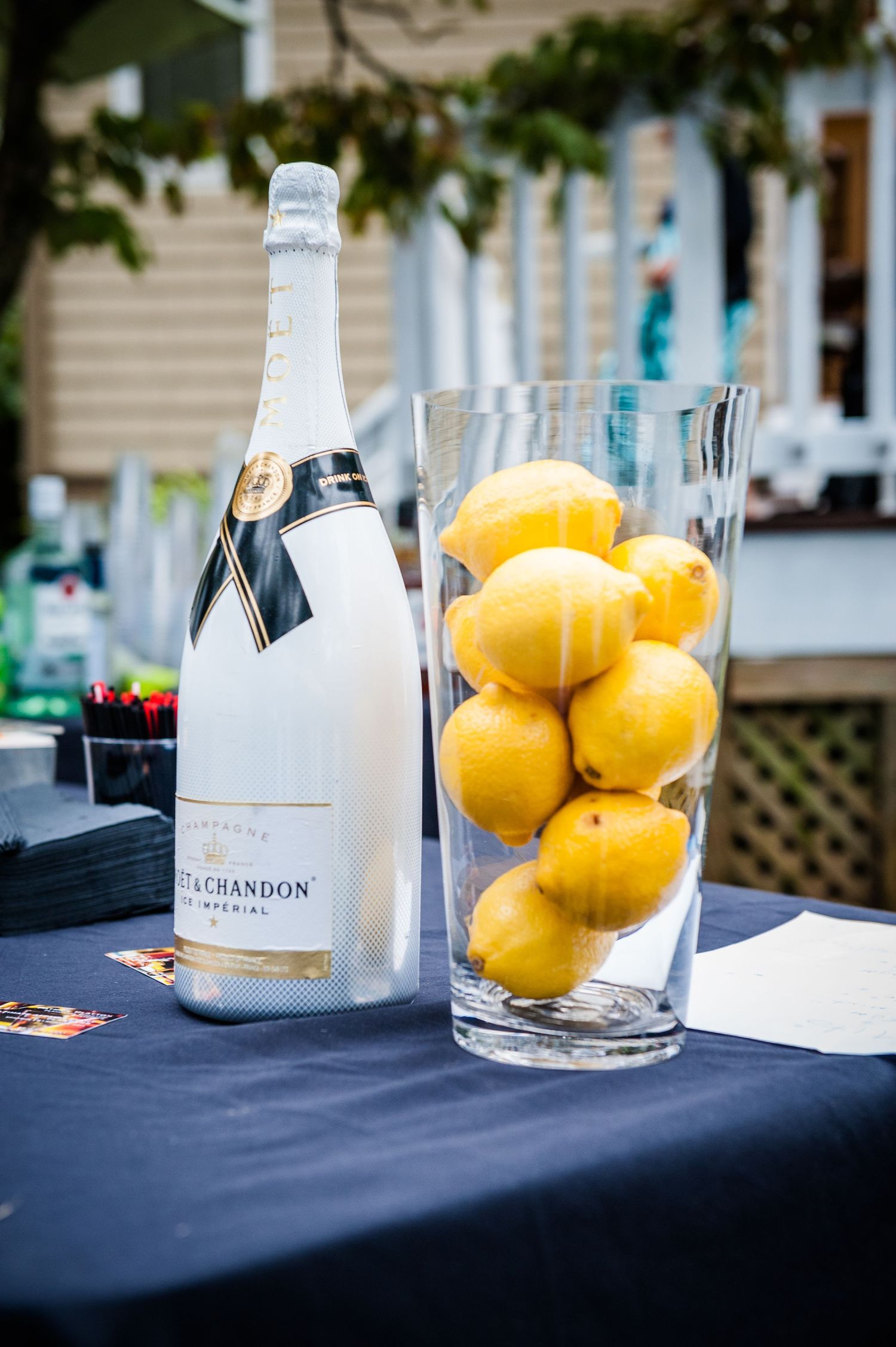 Moet and Chandon Imperial champagne bottle beside a vase of fresh lemons on a table.