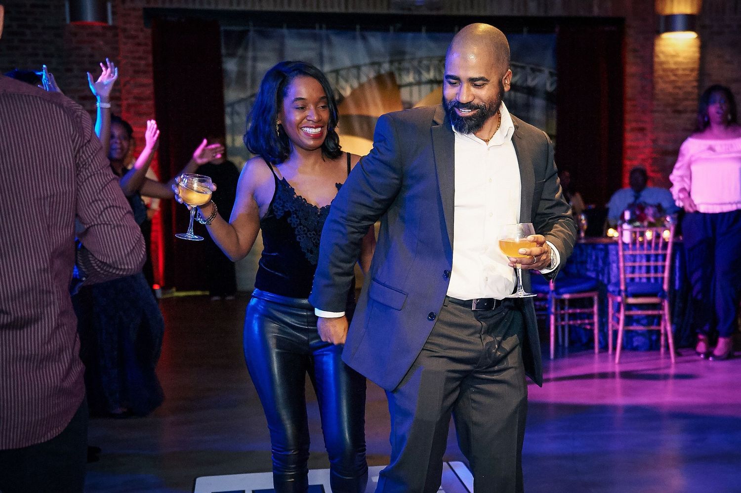 Stylish couple dancing with drinks in hand at a lively celebration, captured using on-camera flash during a candid party event photography s