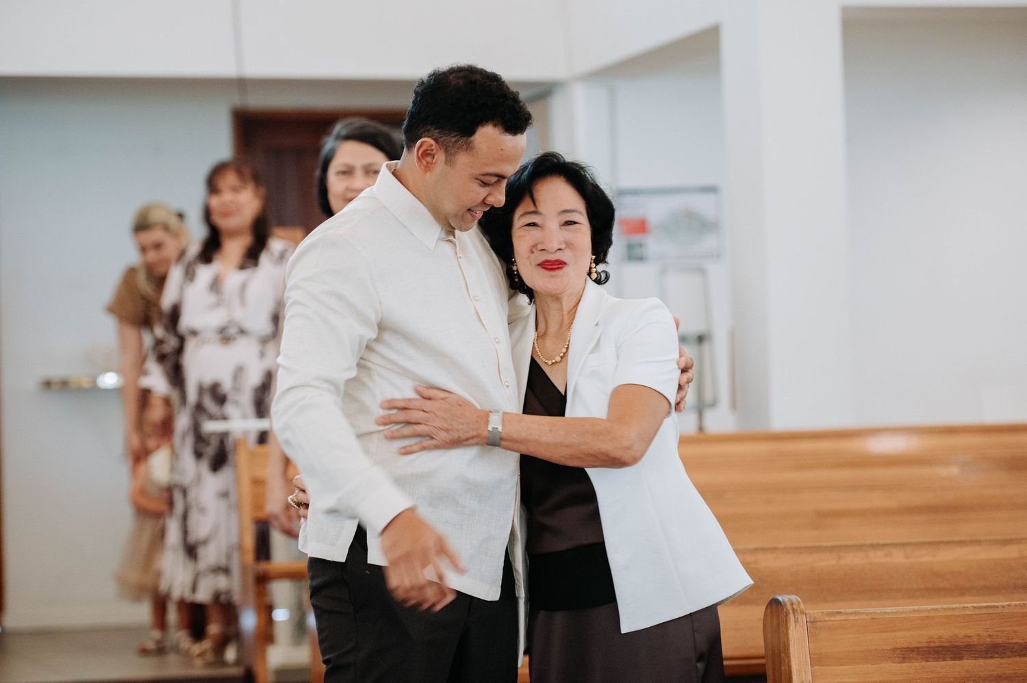 A couple sharing a tender moment while dancing together in a bright interior space with wooden floors.