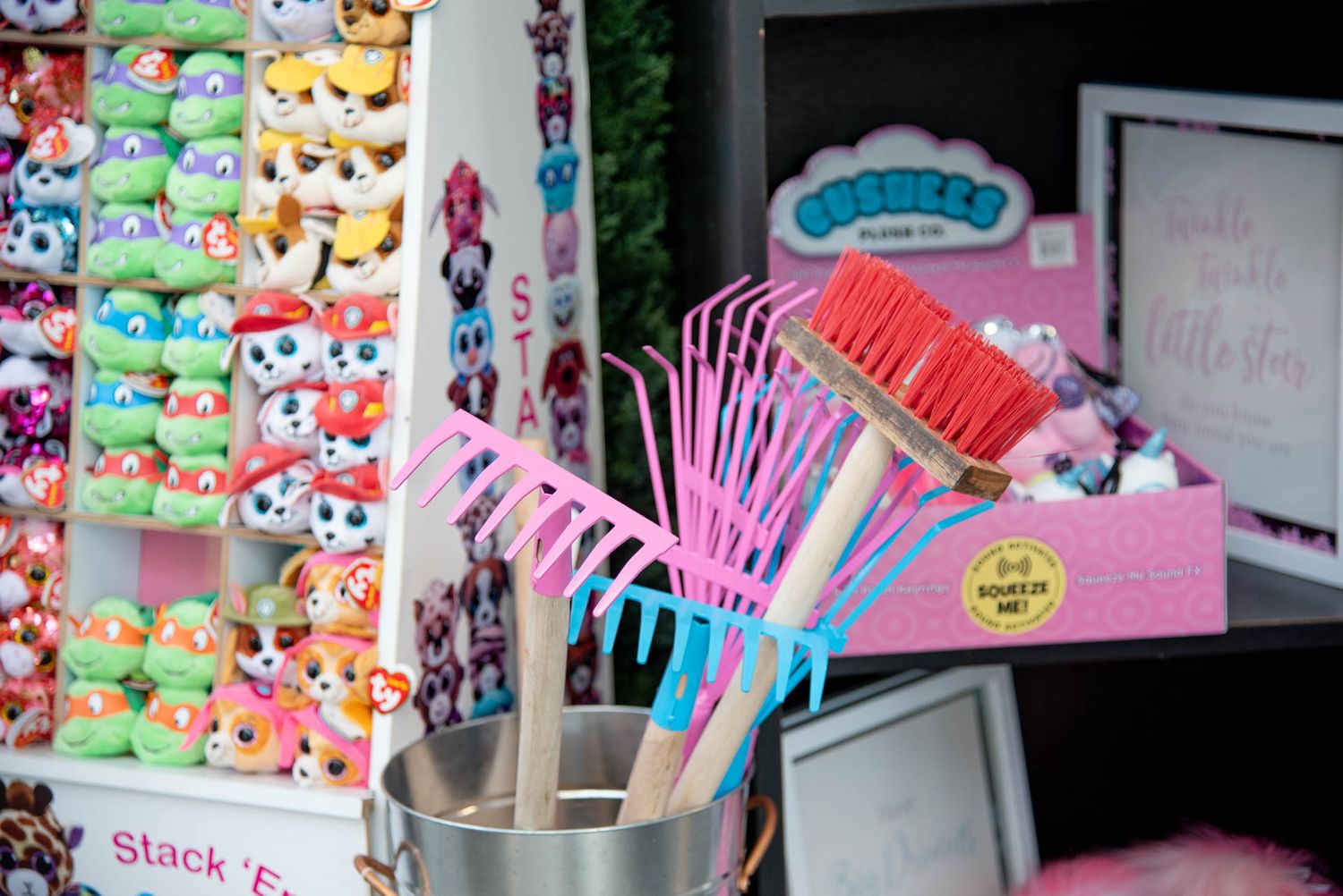 Colorful display of plush toys and pink cleaning supplies including brooms and dustpans at retail store Bradford Greenhouse in Barrie