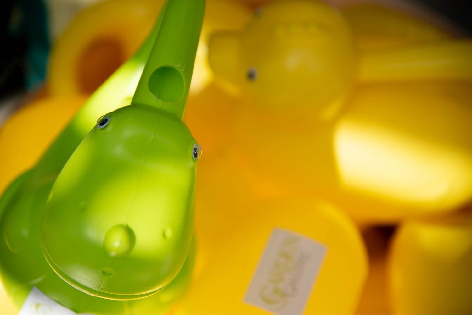 Close-up of a bright green plastic toy against a blurred yellow background at Bradford Greenhouse in Barrie