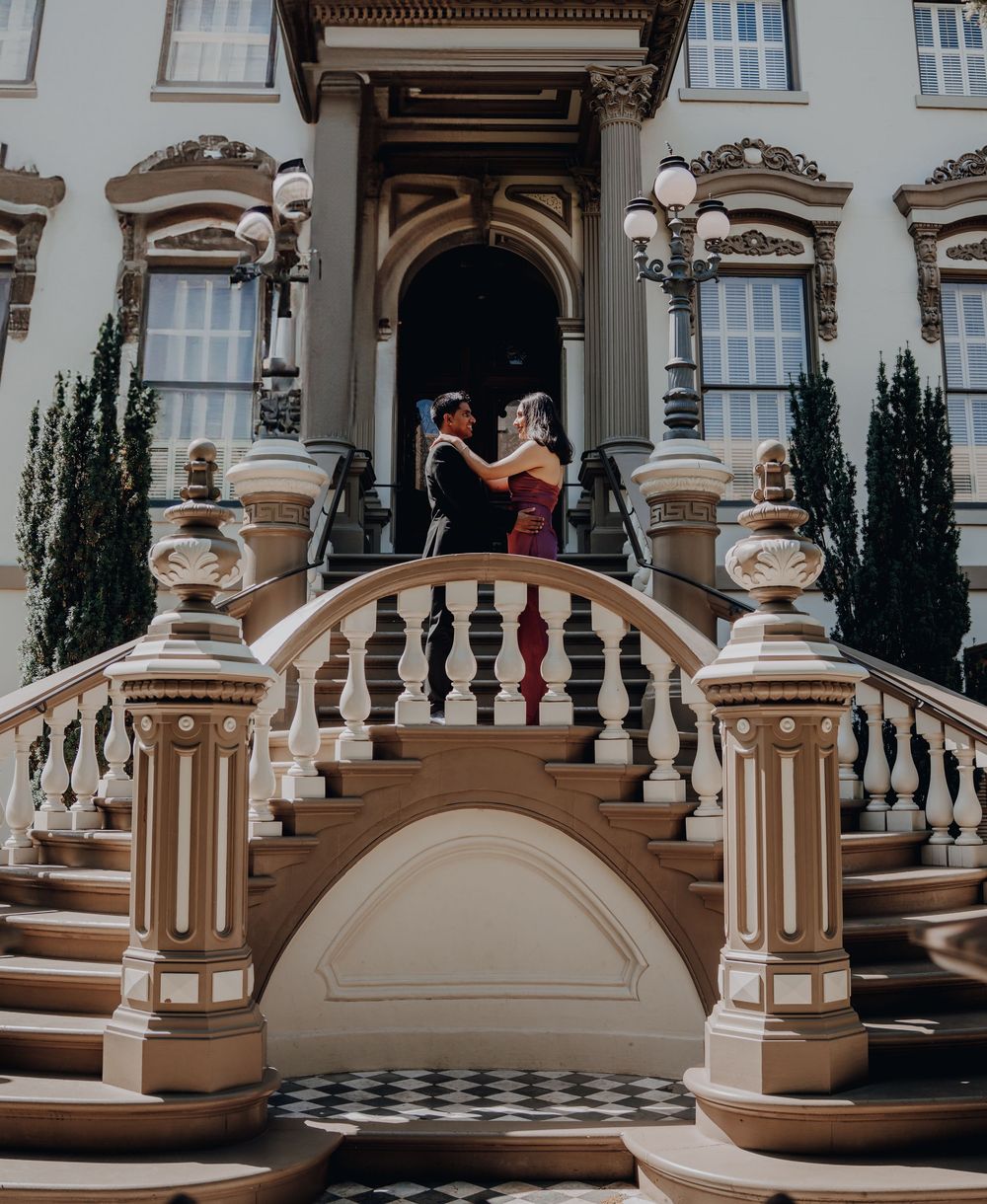 Elegant staircase entrance to a historic mansion with ornate balustrades and cypress trees flanking the stone steps.