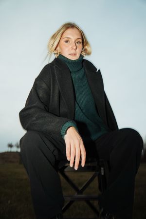 Fashion portrait featuring black coat and dark turtleneck in natural lighting.