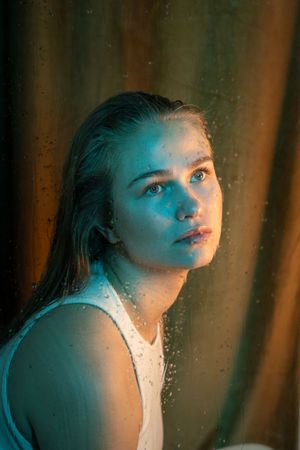 Close-up portrait illuminated by contrasting cool blue and warm lighting effects.