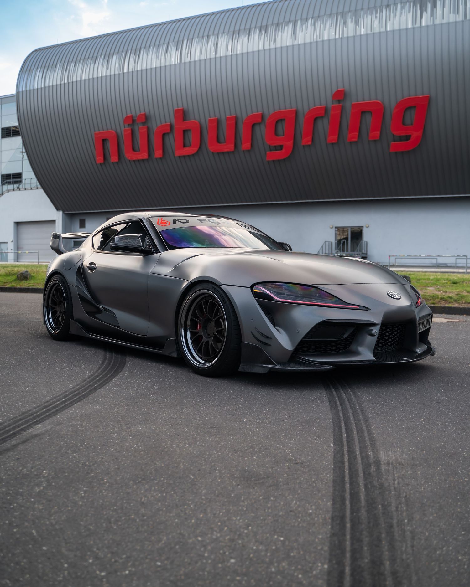 Modified Toyota Supra performing burnouts near Nurburgring signage.