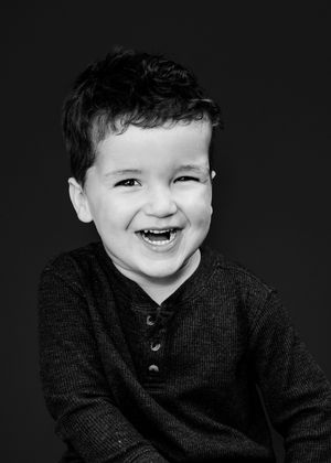 A series of black and white photos showing joyful expressions and laughter in a dark sweater against a black background.