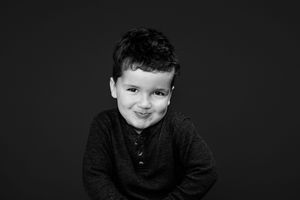 A collage of black and white portrait photos shows smiling expressions against dark backgrounds.