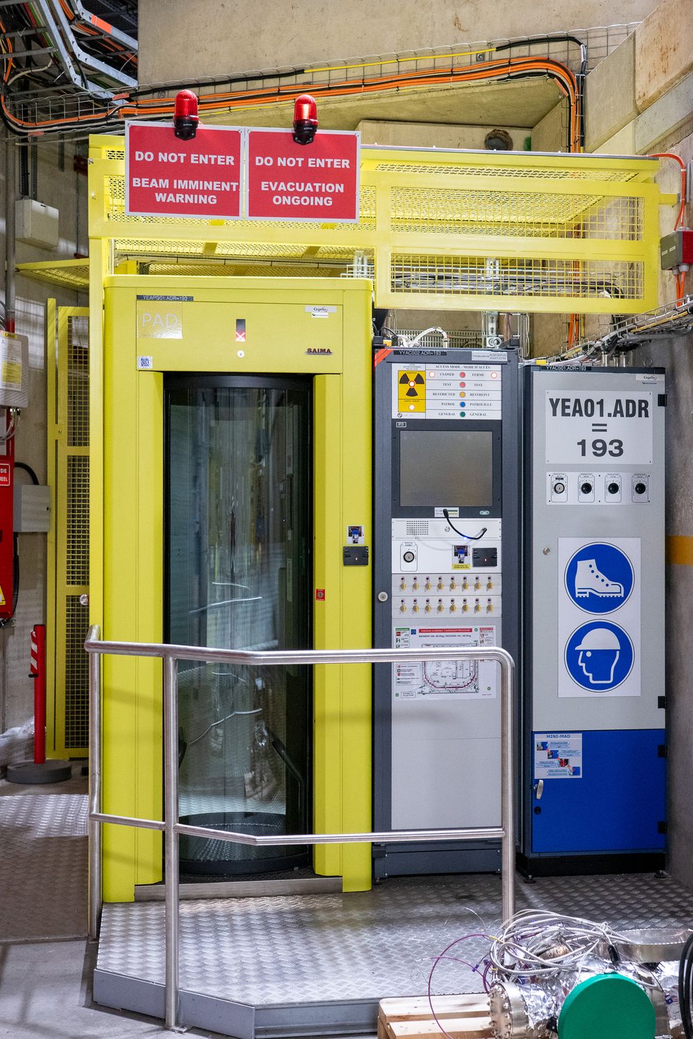 Industrial machinery and equipment panels with safety signs mounted on yellow structural frames inside a manufacturing facility.