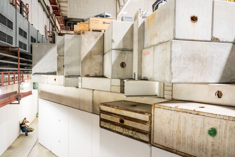 Weathered white concrete stadium seating with tiered rows and wooden panels visible in an indoor stadium section.