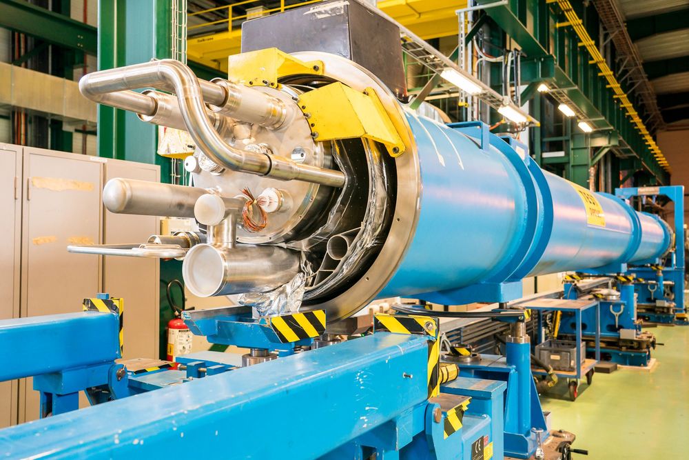 Panoramic view of industrial equipment in a factory with blue and yellow machinery components and pipelines.