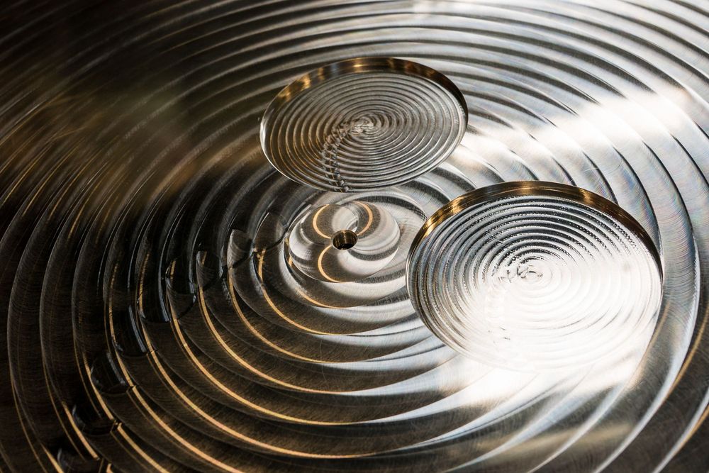 Abstract ripple patterns of polished metal surface reflecting light in concentric circles.