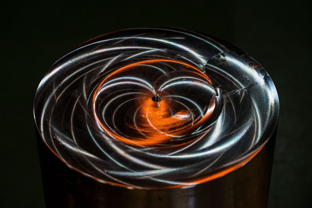 Long exposure photography captures glowing spiral light trails against dark background creating mesmerizing pattern.